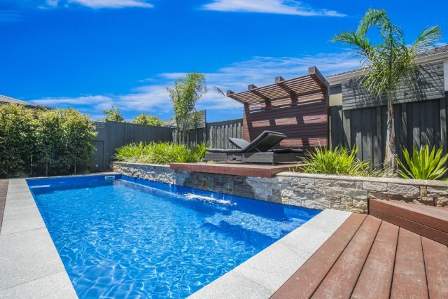 Pool with retaining wall, water feature and sun deck.
